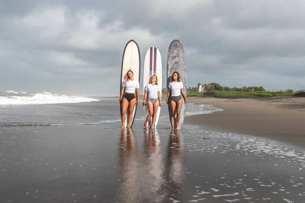 Flickor surfare stå med brädor på stranden. — Stockfoto