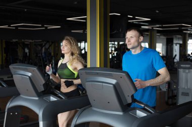 Spor salonunda koşan bir çift.,