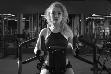 Kız spor salonunda bir kürek simülatörü meşgul.