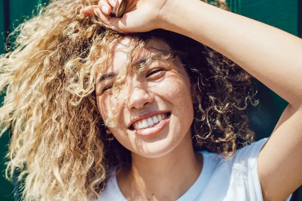 Portret van een lachende jonge vrouw met krullend haar en sproeten. — Stockfoto