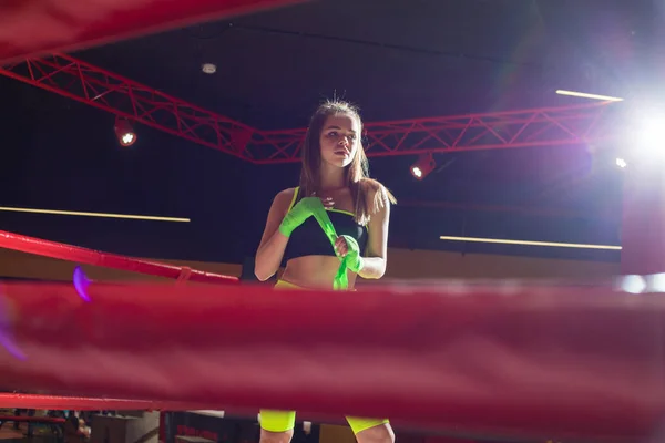 Atletisk flicka som står i ringen och rullar boxning bandage. Boxer flicka i neon leggings. — Stockfoto