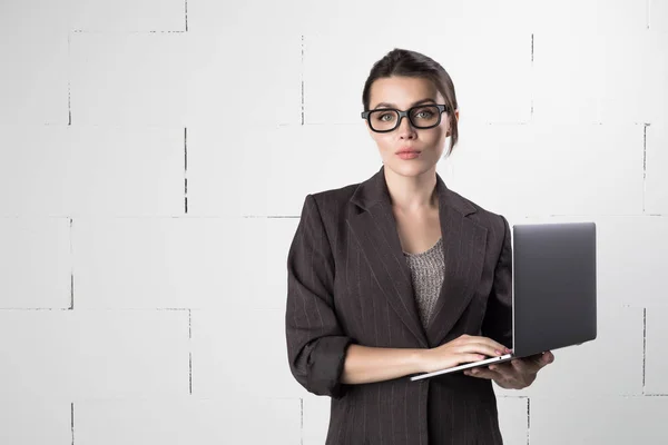 Business woman in glasses and suit with a laptop in hand on white background.