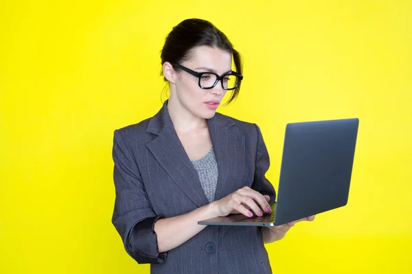 Επιχείρηση γυναίκα σε φόρμα με ένα φορητό υπολογιστή στο χέρι σε κίτρινο φόντο. — Φωτογραφία Αρχείου