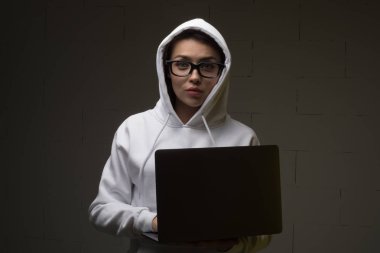 Kapüşonlu bir kadın dizüstü bilgisayar kullanıyor. Hacker bir dizüstü bilgisayar kullanıyor.