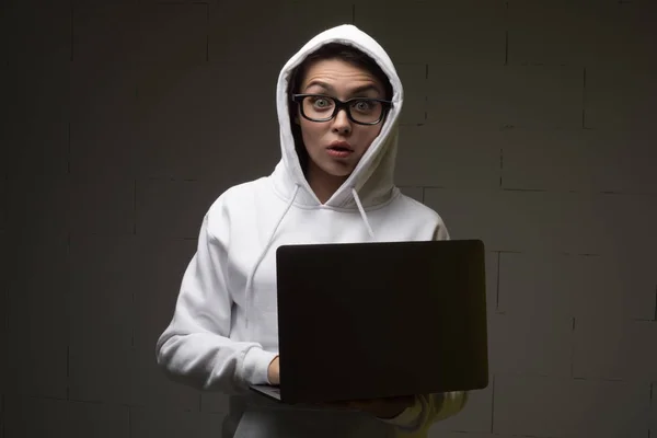 Una mujer con capucha está usando un portátil. Hacker está usando un portátil . — Foto de Stock