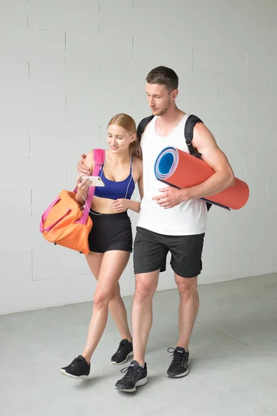 Sport par går tillsammans till gymmet och använda en smartphone. — Stockfoto