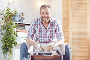 Bir erkek çömlekçi bir atölyede bir çömlek tekerleği üzerinde çalışır.