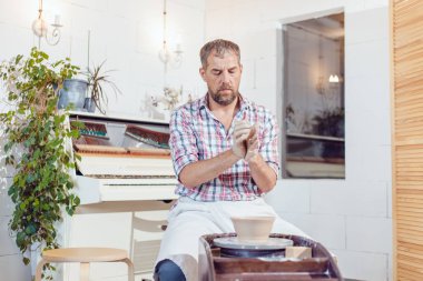 Bir erkek çömlekçi bir atölyede bir çömlek tekerleği üzerinde çalışır.