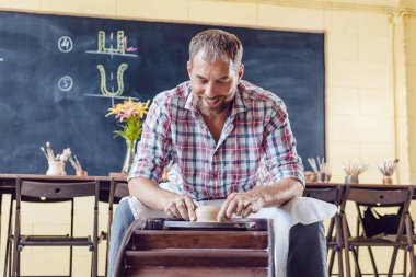 Bir erkek çömlekçi bir atölyede bir çömlek tekerleği üzerinde çalışır.