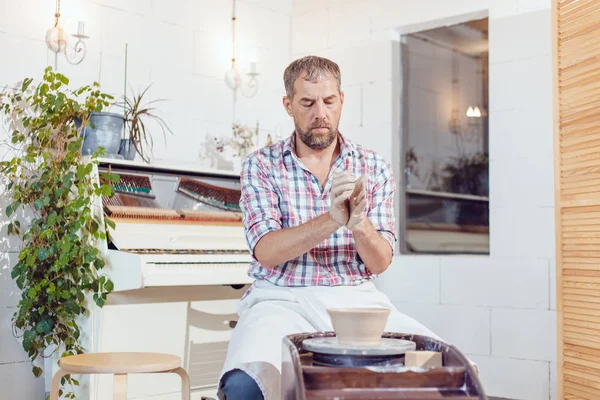 Bir erkek çömlekçi bir atölyede bir çömlek tekerleği üzerinde çalışır.