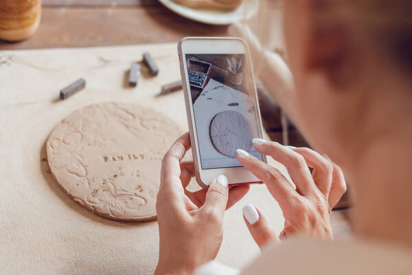 Woman makes a photo of her work from clay with the words "family".