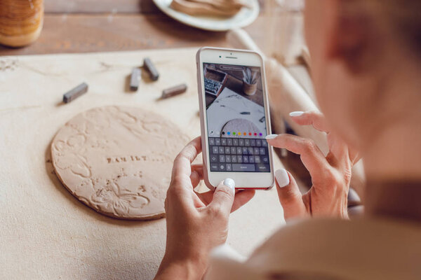 Woman makes a photo of her work from clay with the words "family".