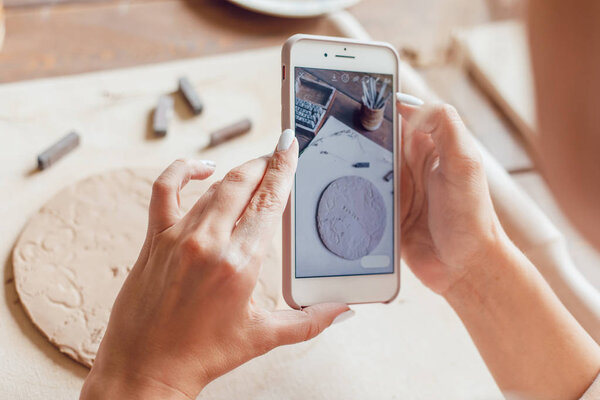 Woman makes a photo of her work from clay with the words "family".