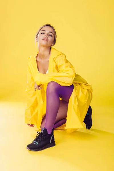 Jovem mulher de capa amarela, calças roxas e tênis . — Fotografia de Stock