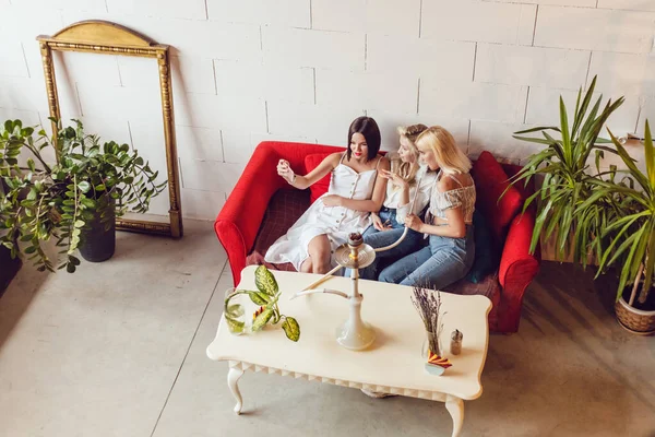 Tres chicas novias están sentadas en un café, charlando y fumando una cachimba . — Foto de Stock