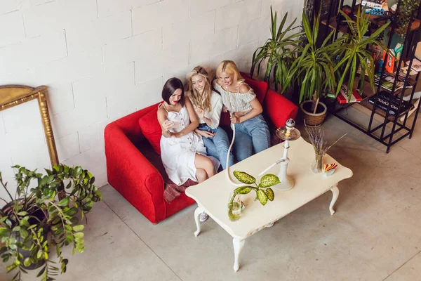 Tres chicas novias están sentadas en un café, charlando y fumando una cachimba . — Foto de Stock