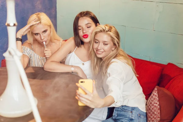 Jovens mulheres bonitas fazem selfie em um lugar de narguilé . — Fotografia de Stock
