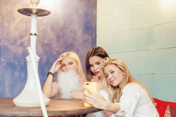 Jovens mulheres bonitas fazem selfie em um lugar de narguilé . — Fotografia de Stock