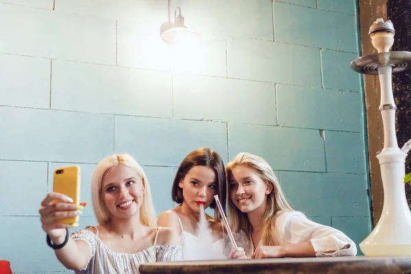 Jovens mulheres bonitas fazem selfie em um lugar de narguilé . — Fotografia de Stock