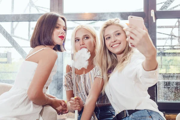 Hermosa joven fumando una cachimba y hacer selfie . — Foto de Stock