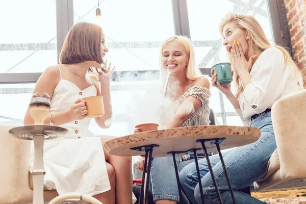 3人の女の子のガールフレンドは、カフェに座っている、チャットや喫煙aフカ. — ストック写真