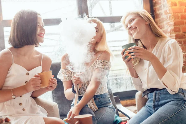 Tre flickvänner sitter på ett kafé och pratar och röker en hora.. — Stockfoto