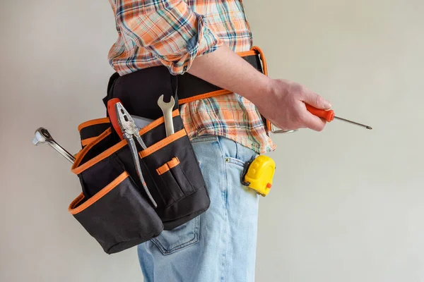 The Builder is holding a screwdriver, and in the waist bag-tools for repair.