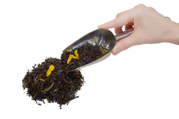 Изолировать, женская рука держит ложку наполненную сухими листьями чая, выливает его на стол — стоковое фото