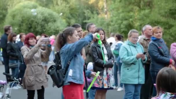 Wolonia, Rosja, lipiec 2019: dziewczyna tworzy, napełnia ogromne bańki mydlane piankowe party — Wideo stockowe