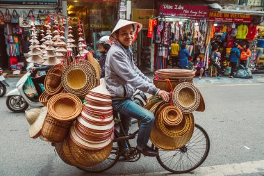 HANOI, VİETNAM - 14 Aralık 2018 Hanoi 'nin Eski Mahallesi. Sokak satıcısı bisikletten çeşitli geleneksel Vietnam şapkaları satıyor.