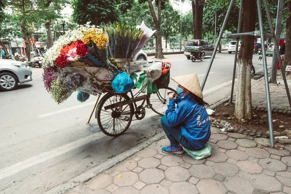 HANOI, VİETNAM - 14 Aralık 2018: Sabah sokak pazarının yerel yaşamı, sokak satıcıları bisikletlerinden çeşitli türde çiçekler satıyorlar