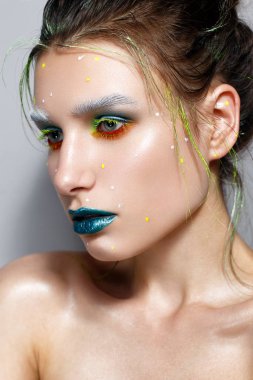 Yaratıcı çok renkli makyaj ile genç kız. Parlak neon renkler. Turkuaz dudaklar ve parlayan cilt. Kozmik görüntü. Yüz güzelliği. Fotoğraf stüdyosunda alınır.