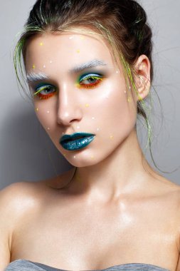Yaratıcı çok renkli makyaj ile genç kız. Parlak neon renkler. Turkuaz dudaklar ve parlayan cilt. Kozmik görüntü. Yüz güzelliği. Fotoğraf stüdyosunda alınır.