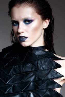 Gotik tarzı parlak ve parlak bir makyaj ile genç bir kız. Güzel model parlak deri ve deri elbiseli. Stüdyoda yapılan portre.