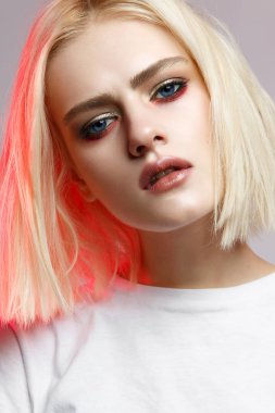 Nazik bir yaratıcı makyaj ile beyaz t-shirt bir genç kız withblond saç. Cilt ve çıplak parlayan ile güzel bir model. Stüdyoda yapılan portre. Renk filtreleri.
