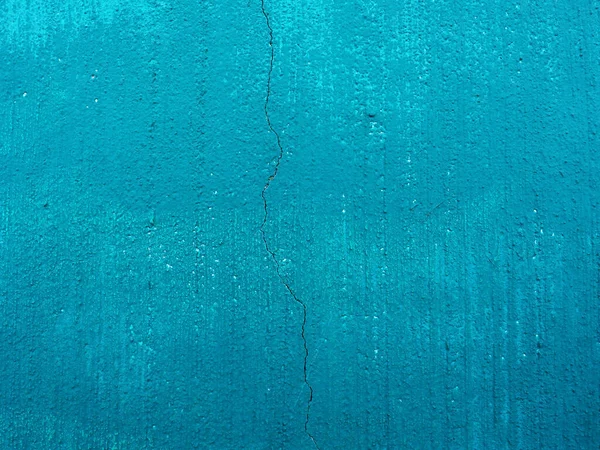 concrete wall painted with light blue paint with crack