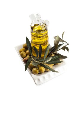 Şeffaf bir şişe zeytinyağı. Zeytin, zeytin bir tabak içinde bırakır. Beyaz bir arka plan üzerinde