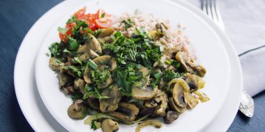 Kırmızı Pirinç mantar ve kiraz domates. Vegan yemek. Avrupa mutfağı. Basit sağlıklı öğle yemeği. Vejetaryen pirinç beyaz tabak çanak. Yakın çekim. Geniş fotoğraf.