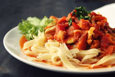 Şerit Arrabiata soslu makarna. Yakın çekim. Akdeniz çanağı. Tagliolini sebzeli makarna. Karnabahar, kabak ve domates yahnisi. İtalyan mutfağı. Vegan ve vejetaryen.