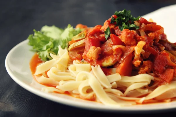 Şerit Arrabiata soslu makarna. Yakın çekim. Akdeniz çanağı. Tagliolini sebzeli makarna. Karnabahar, kabak ve domates yahnisi. İtalyan mutfağı. Vegan ve vejetaryen.