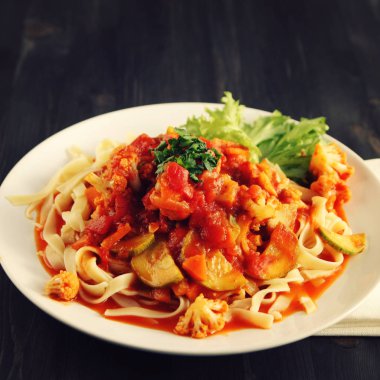 Şerit Arrabiata soslu makarna. Yakın çekim. Akdeniz çanağı. Tagliolini sebzeli makarna. Karnabahar, kabak ve domates yahnisi. İtalyan mutfağı. Vegan ve vejetaryen. Tonda fotoğraf.