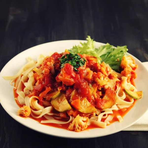 Şerit Arrabiata soslu makarna. Yakın çekim. Akdeniz çanağı. Tagliolini sebzeli makarna. Karnabahar, kabak ve domates yahnisi. İtalyan mutfağı. Vegan ve vejetaryen. Tonda fotoğraf.