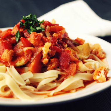 Şerit Arrabiata soslu makarna. Yakın çekim. Akdeniz çanağı. Tagliolini sebzeli makarna. Karnabahar, kabak ve domates yahnisi. İtalyan mutfağı. Vegan ve vejetaryen. Tonda fotoğraf.