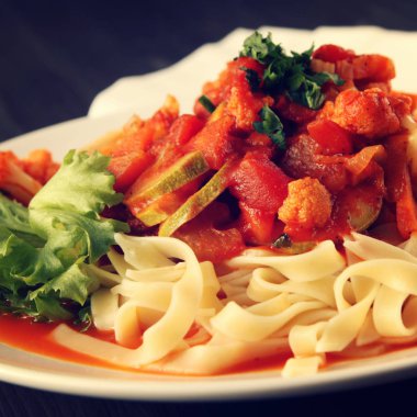 Şerit Arrabiata soslu makarna. Yakın çekim. Akdeniz çanağı. Tagliolini sebzeli makarna. Karnabahar, kabak ve domates yahnisi. İtalyan mutfağı. Vegan ve vejetaryen. Tonda fotoğraf.