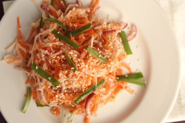 Vejetaryen havuç ve turp salatası. Asya mutfağı. Yuvarlak plaka üzerinde sağlıklı vejetaryen meze. Garnitür. Basit düşük kalori öğle yemeği. Üstten görünüm.