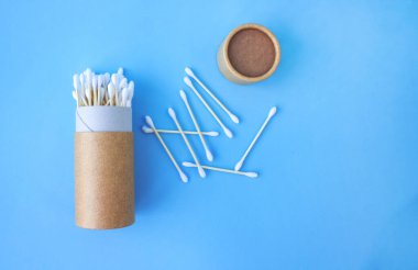 Mavi arka planda bambu pamuk çubuklarıyla yeniden kullanılabilir kağıt ambalaj tüpünün içinde düz bir bileşim yatıyordu. Tasarımınız için kopyalama alanı, sıfır atık kavramı. Model
