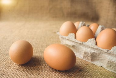 Güneşli bir günde, kağıt ambalaj kutusunda duran yerel çiftçi pazarından taze organik tavuk yumurtalarına ön manzara. Sağlıklı organik gıda konsepti. Metin veya sunumunuz için kopyalanma alanı
