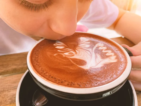 Genç bir çocuğun kakao içtiği ya da evde latte sanatıyla sıcak çikolata içtiği bir sahne. Sonbahar ya da Noel tatillerinde geleneksel sıcak içecek. Kahvaltıda bir fincan sıcak kakao.