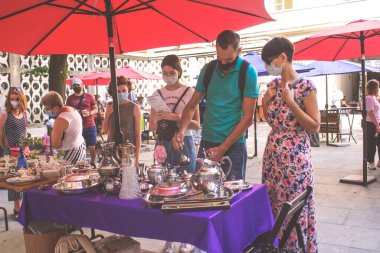 Lviv, Ukrayna - 09 Ağustos 2020: Belediye binasında yazlık garaj satışı, Tlum ve Kram. Tek kullanımlık koruyucu maskeler takan insanlar bit pazarından ikinci el mal alıyor, ikinci el alışveriş konsepti.