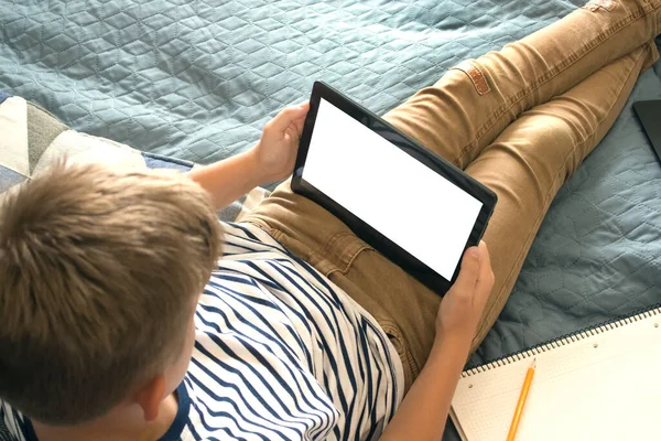 Bovenaanzicht op jongen schrijven of tekenen en het gebruik van zijn tablet tijdens het doen van huiswerk. Online studeren tijdens quarantaine, online trainingen of persoonlijk onderwijsplan concept. Terug naar school. Gezichtsloos — Stockfoto